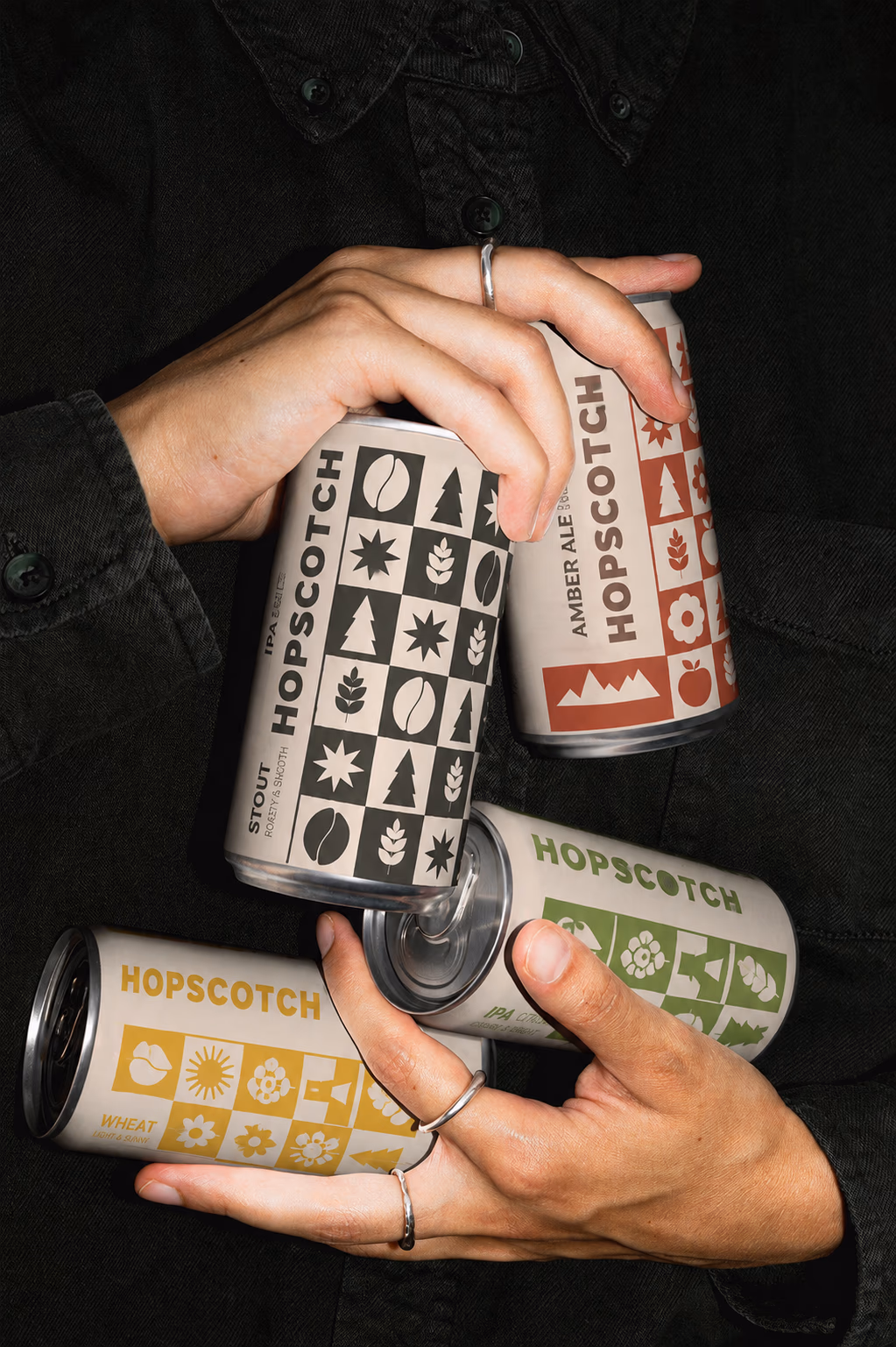 Hands holding Hopscotch beverage cans